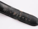 an old watch strap with holes in it on a white surface