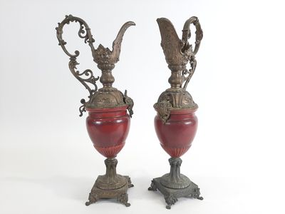 paire de vases rouges munis d'anses, posés sur des socles, sur fond blanc