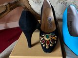 pair of black and blue high heel shoes on a box next to a chair