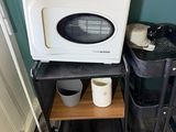 a microwave sitting on top of a cart in the corner of a room