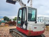 a red and white excavator that is on the ground