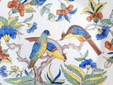 two birds sitting on a plate with flowers and leaves