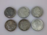 six pièces de monnaie britanniques différentes empilées les unes sur les autres sur une surface blanche