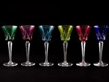 six verres à vin de couleurs différentes alignés sur un fond noir