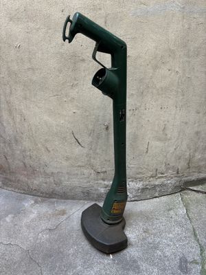 une pompe à eau verte posée sur le trottoir, près d'un mur