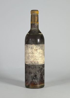 une vieille bouteille de vin posée sur une table blanche