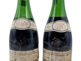 deux bouteilles de vin sont posées l'une à côté de l'autre sur une surface blanche
