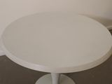 a white round table with a white base on the floor