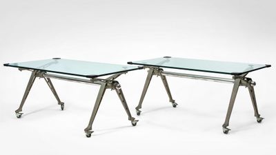 a pair of glass tables with metal legs on wheels