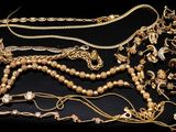 several gold necklaces and bracelets are arranged on a black surface