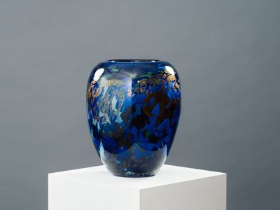 un vase bleu posé sur un socle blanc