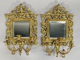 une paire de miroirs dorés accrochés au mur, avec des bougies et un bougeoir