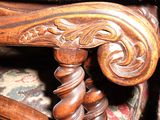 a close up of a wooden chair with a black cat sitting on it