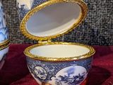 three blue and white porcelain eggs sitting on a red cloth