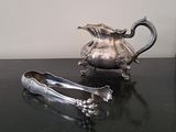 a silver pitcher and a pair of tonges on a table