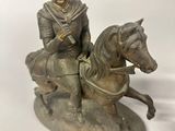 a statue of a man riding a horse on a white surface