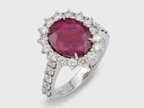 a close up of a ring with a ruby stone surrounded by diamonds