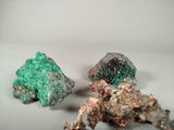two pieces of green and brown colored rocks on a white surface