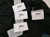 several tags are attached to a black jacket on a white surface
