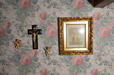 un tableau accroché au mur, au-dessus d'un crucifix et d'une croix