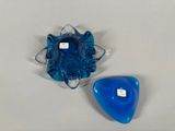 two pieces of blue glass sitting on a white surface