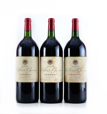 trois bouteilles de vin rouge sont alignées sur une surface blanche