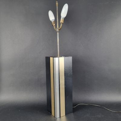 une lampe de table noire et dorée surmontée de trois ampoules