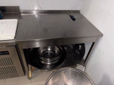 un plan de travail en acier inoxydable sur lequel sont posés un saladier et une casserole