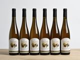 six bottles of wine are lined up on a wooden table
