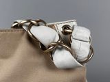 a close up of a beige and white purse with a chain around it