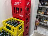 bottles of soda and soft drinks are stacked on crates in a store