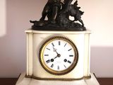 une horloge surmontée d'une statue, posée sur une table