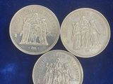 three british silver sovereigns on a blue velvet surface