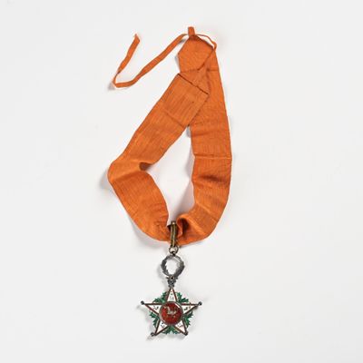 an orange ribbon with a silver star and a red rose on it