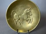 assiette en or décorée d'un cheval, posée sur un socle en métal