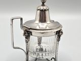 une théière en métal plaqué argent, munie d'un couvercle en verre et d'une anse