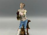 figurine représentant un homme assis sur une souche d'arbre, tenant un panier de fleurs