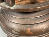 a large bronze pot with a handle on a stand