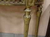 a gold table with a marble top on a tile floor