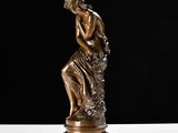 a bronze statue of a man sitting on top of a table