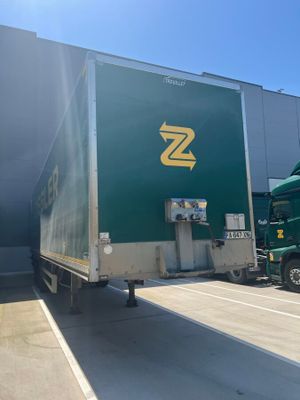 a green semi truck that is parked in front of a building