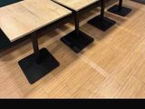 trois tables en bois posées sur un parquet, à côté d'un mur vert