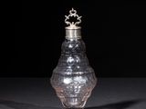 an old silver vase with a crown on top on a black surface