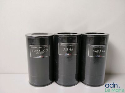 trois bidons noirs portant des étiquettes, posés sur une table