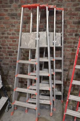 trois échelles appuyées contre un mur de briques