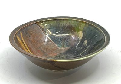 un bol marron et vert posé sur une surface blanche