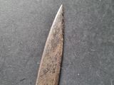 a knife that is laying on a table next to a piece of paper