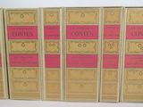 six books in a row on a white surface with pink covers