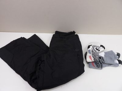 un pantalon noir et une peluche posés sur une table blanche