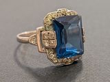 a close up of a ring with a blue stone in it